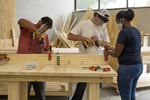 3 Building Construction student work with power tools to build a table