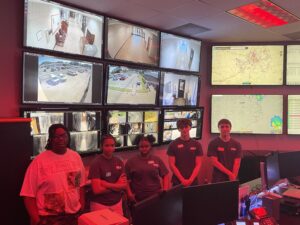 SEED students posing in front of a wall of TV screens