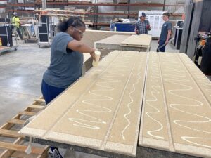 SEED student applying adhesive to a large board