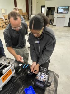 Instructor guiding a SEED student using an electric tool