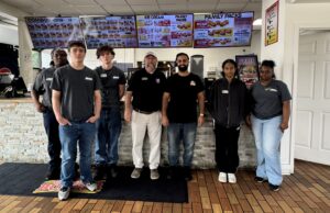 SEED students posing at the front of a restaurant with their instructor and the business manager